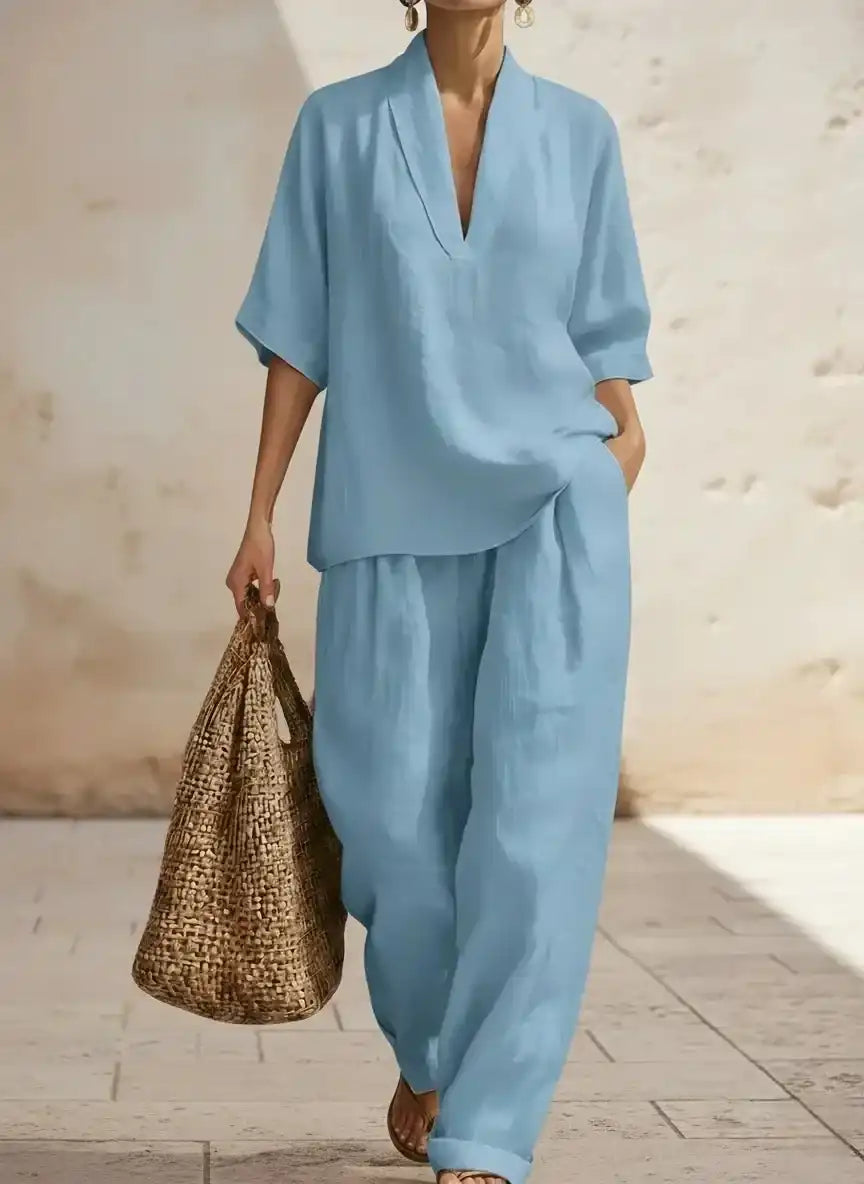 Light blue linen pajama set with V-neck top and wide-leg pants, paired with woven tote bag for relaxed style.