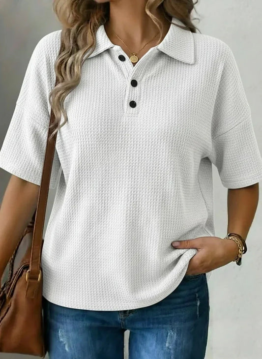 White textured polo shirt with black buttons, relaxed fit, paired with jeans and brown bag for casual style