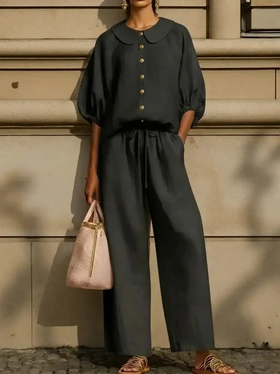 Black Peter Pan collar blouse with gold buttons, wide-leg pants, and pink tote bag for sophisticated women