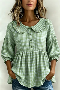 Green gingham blouse with ruffled collar and puff sleeves, styled with jeans for a relaxed fit.