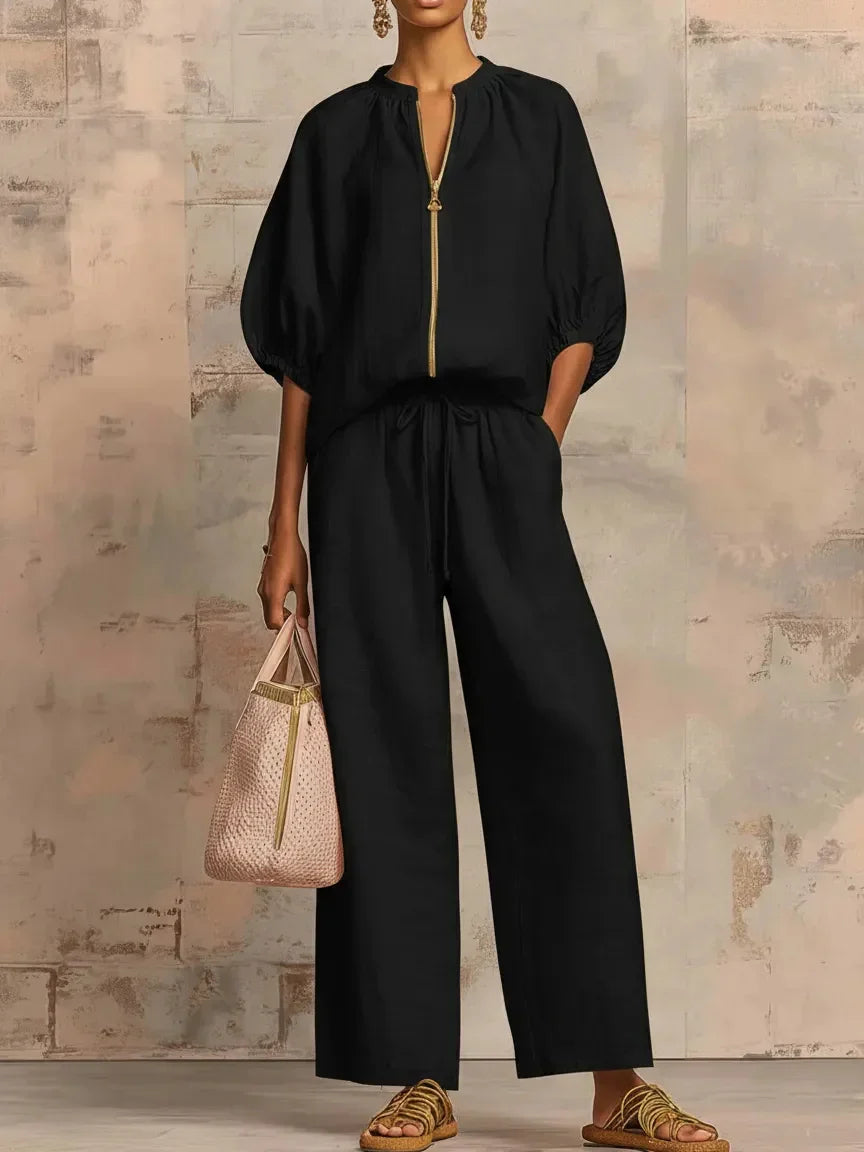 Black relaxed fit jumpsuit with gold zipper, wide legs, and drawstring waist for sophisticated women