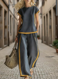 Woman in gray and mustard wide-leg pants set, walking on cobblestone street, stylish plus size outfit
