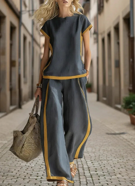Woman in gray and mustard wide-leg pants set, walking on cobblestone street, stylish plus size outfit