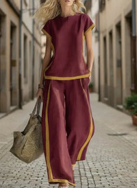 Woman in burgundy plus size matching set with gold trim, walking on cobblestone street, stylish relaxed fit